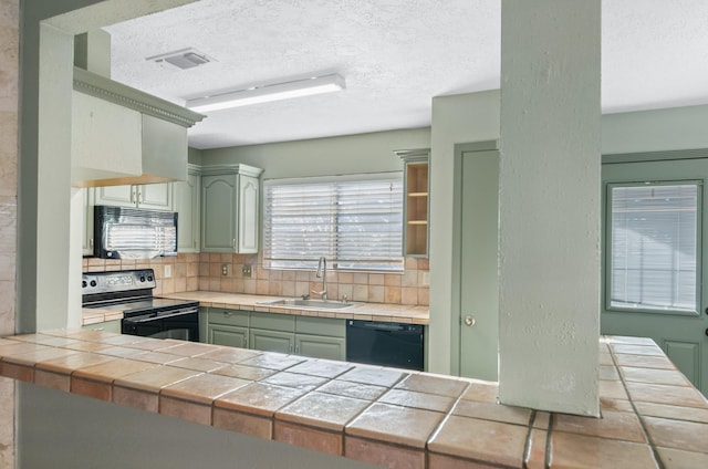 kitchen with black appliances, sink, decorative backsplash, a textured ceiling, and tile counters