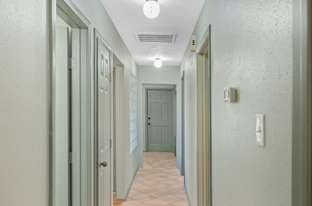 corridor featuring light tile patterned floors and a textured ceiling