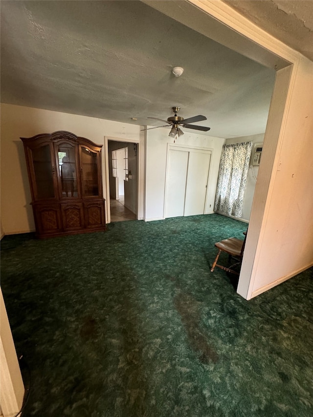 interior space featuring a textured ceiling, dark colored carpet, and ceiling fan