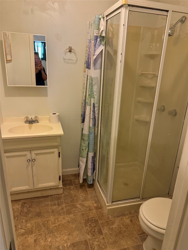 bathroom featuring vanity, toilet, and an enclosed shower