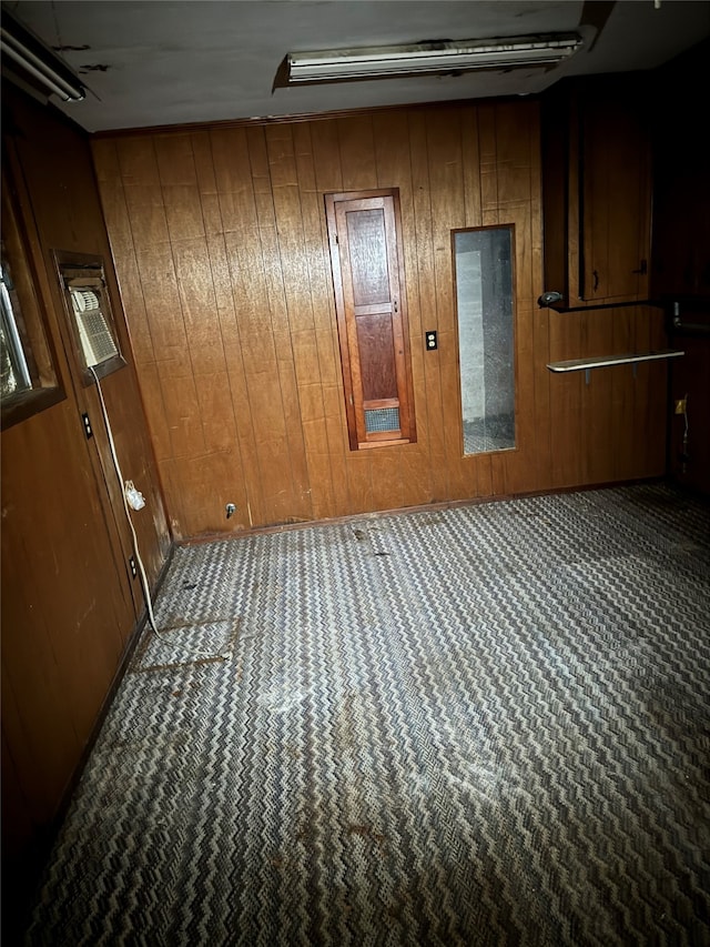 carpeted empty room featuring wood walls