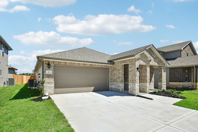 view of front of home with a garage, central AC, and a front yard