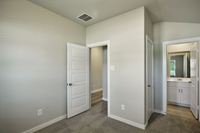 unfurnished bedroom with ensuite bath, sink, and carpet