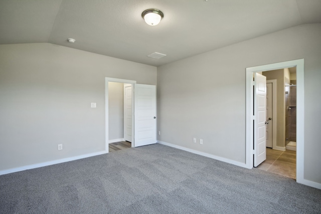 unfurnished bedroom with lofted ceiling, connected bathroom, and light carpet