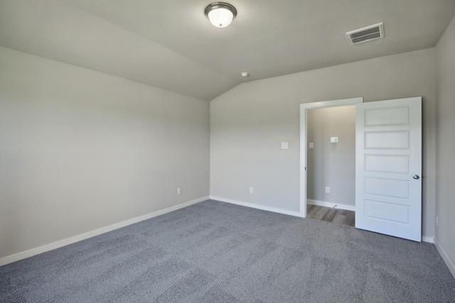 carpeted spare room featuring vaulted ceiling