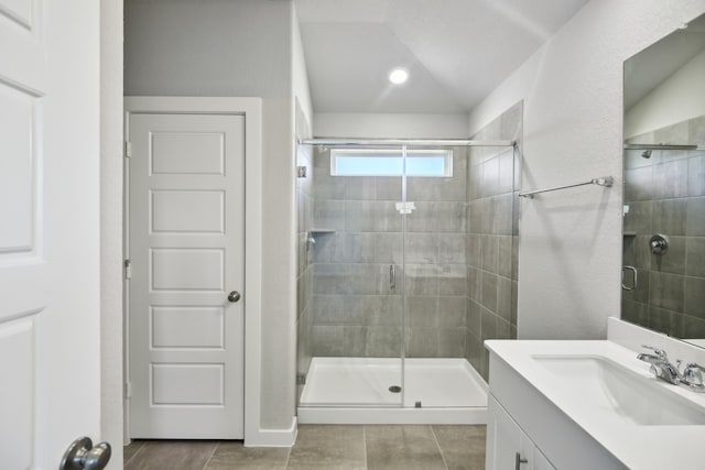 bathroom featuring walk in shower, lofted ceiling, vanity, and tile patterned floors