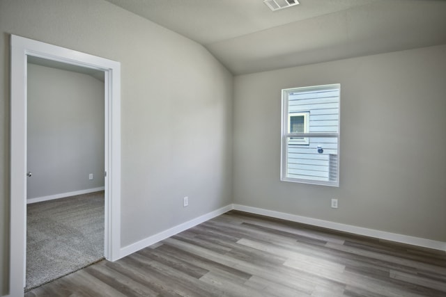 spare room with vaulted ceiling and light wood-type flooring