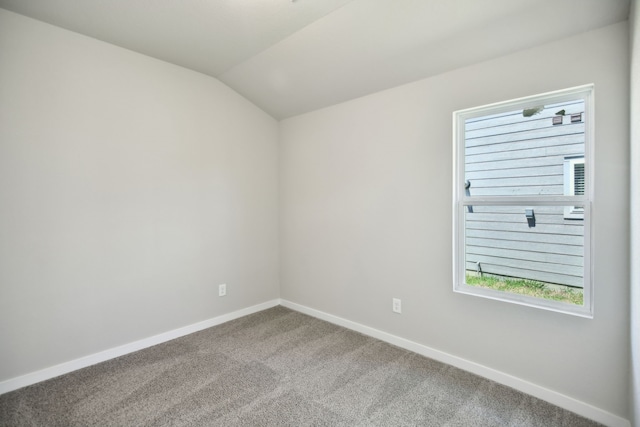 carpeted empty room featuring vaulted ceiling