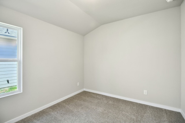 carpeted spare room featuring lofted ceiling