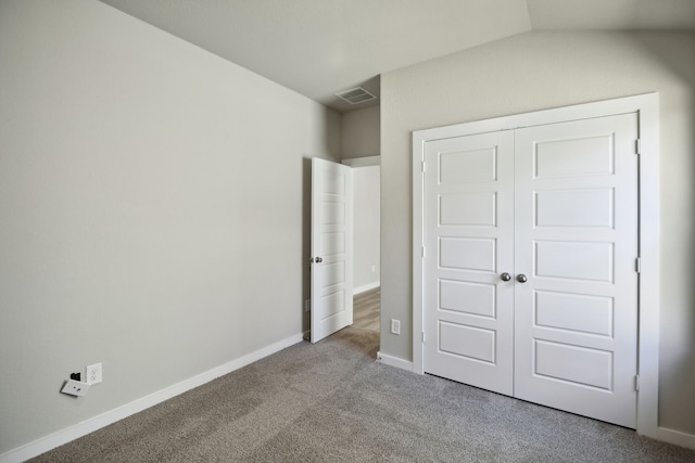 unfurnished bedroom with light colored carpet, vaulted ceiling, and a closet