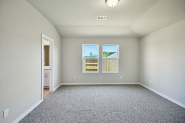 carpeted empty room with vaulted ceiling