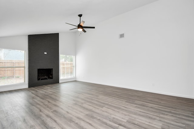 unfurnished living room with a fireplace, plenty of natural light, light wood-type flooring, and lofted ceiling