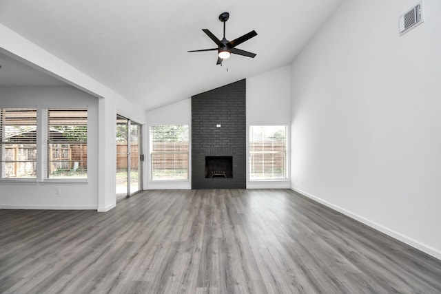 unfurnished living room featuring hardwood / wood-style floors, a wealth of natural light, a fireplace, and high vaulted ceiling