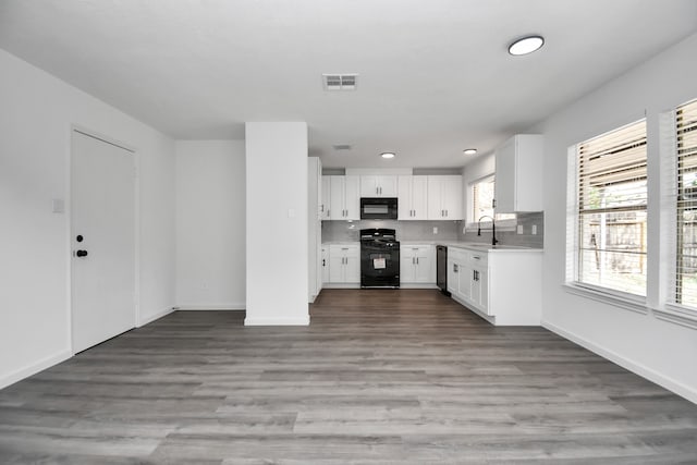 kitchen featuring black appliances, hardwood / wood-style flooring, sink, backsplash, and white cabinetry