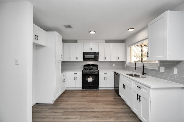 kitchen with black appliances, tasteful backsplash, hardwood / wood-style floors, sink, and white cabinets