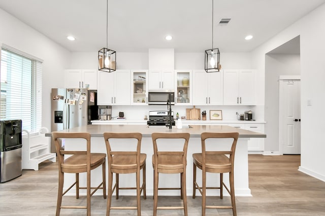 kitchen with stainless steel appliances, a center island with sink, and plenty of natural light