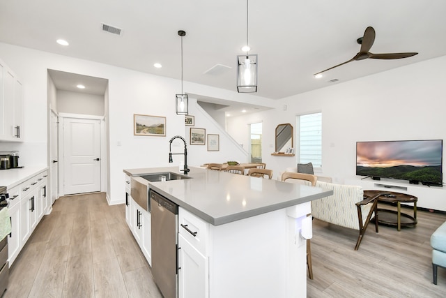 kitchen with a center island with sink, sink, appliances with stainless steel finishes, decorative light fixtures, and white cabinets