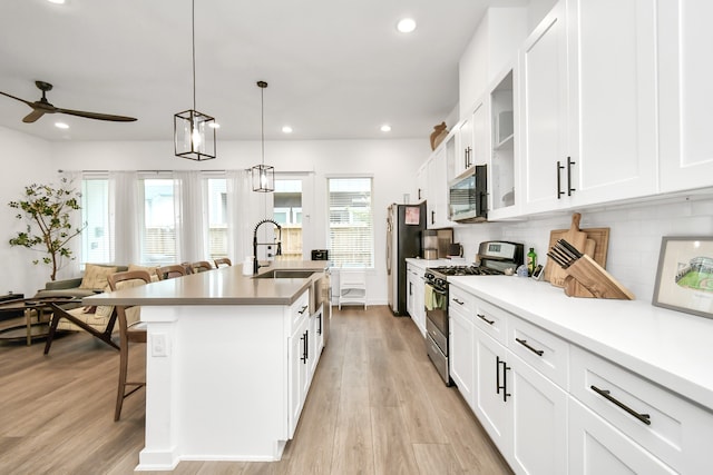 kitchen with white cabinets, decorative light fixtures, and stainless steel appliances