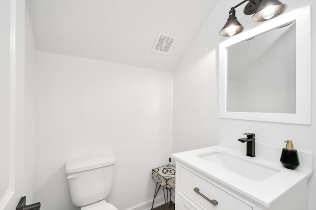 bathroom with vanity, toilet, and lofted ceiling