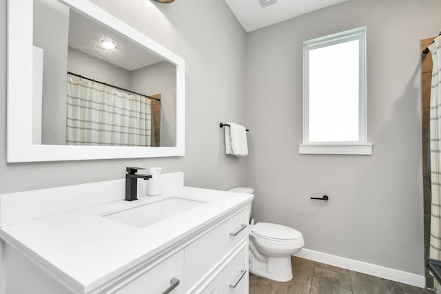 bathroom featuring toilet, vanity, wood-type flooring, and a healthy amount of sunlight