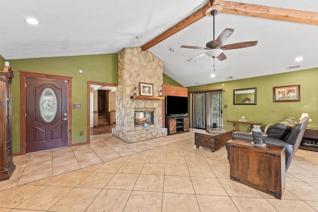 tiled living room featuring a textured ceiling, vaulted ceiling with beams, a fireplace, and ceiling fan