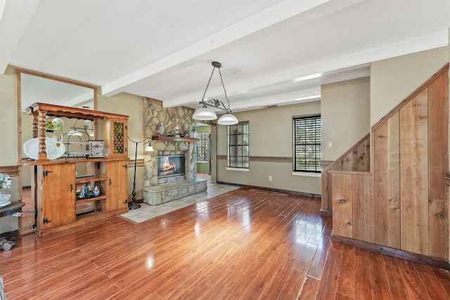 unfurnished living room featuring beam ceiling, wood-type flooring, and a fireplace