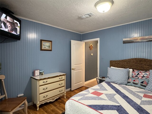 bedroom with a textured ceiling, crown molding, and wood-type flooring