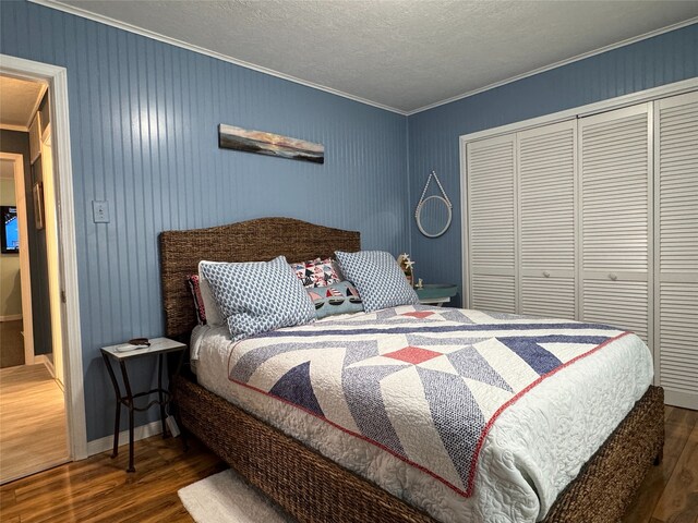 bedroom with a closet, dark hardwood / wood-style flooring, and crown molding