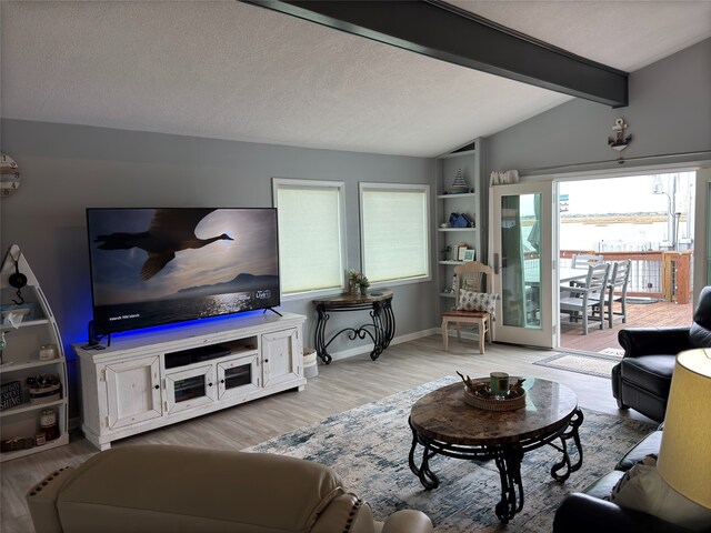 living room with built in features, a wealth of natural light, light hardwood / wood-style floors, and lofted ceiling with beams