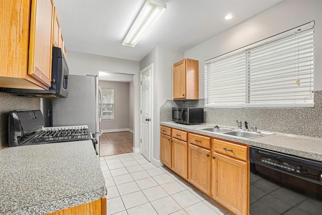 kitchen featuring light tile patterned flooring, sink, backsplash, range, and black dishwasher