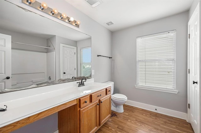 bathroom with wood-type flooring, toilet, vanity, and a shower