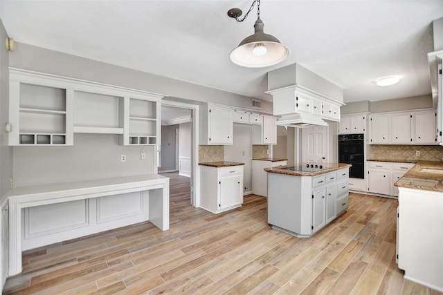 kitchen with backsplash, black appliances, decorative light fixtures, white cabinetry, and light hardwood / wood-style floors