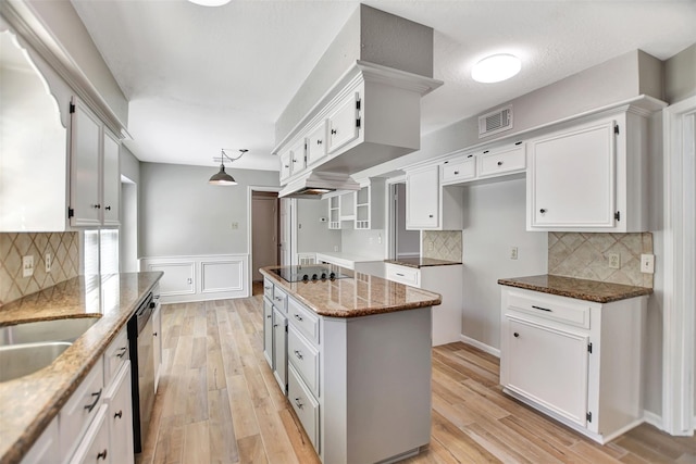 kitchen with light hardwood / wood-style floors, light stone countertops, pendant lighting, and white cabinets