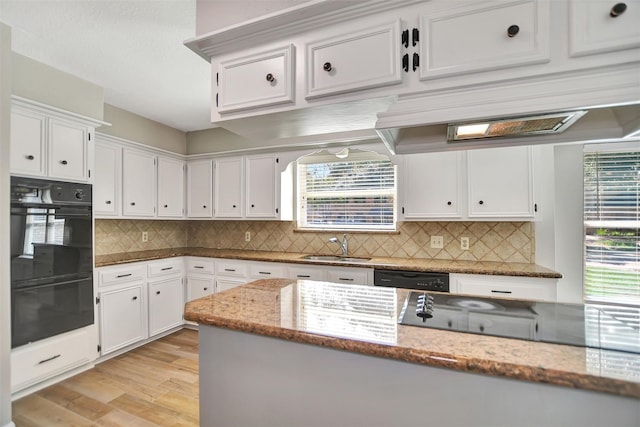 kitchen featuring tasteful backsplash, white cabinetry, light hardwood / wood-style flooring, black appliances, and light stone counters