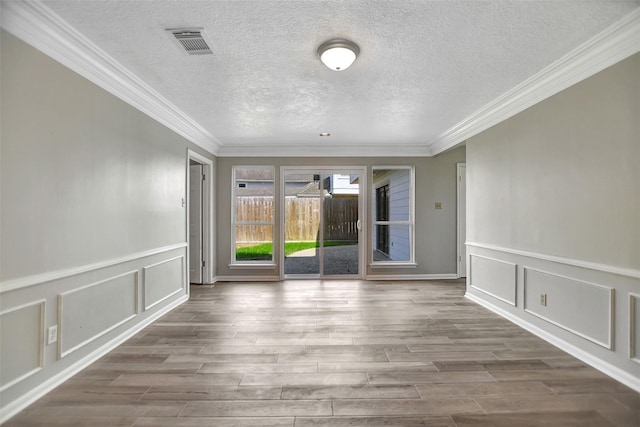 spare room featuring hardwood / wood-style flooring, ornamental molding, and a textured ceiling