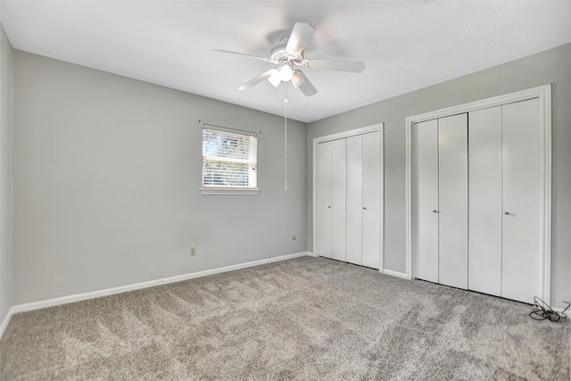 unfurnished bedroom featuring light colored carpet, ceiling fan, and two closets