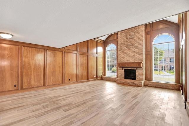 unfurnished living room featuring plenty of natural light, light hardwood / wood-style floors, and wooden walls