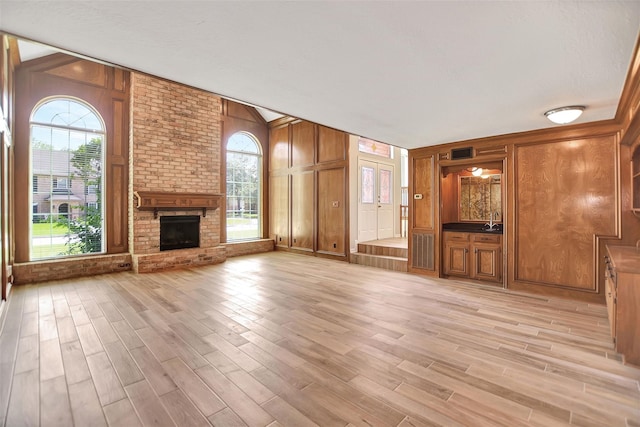 unfurnished living room with light hardwood / wood-style flooring, wooden walls, and plenty of natural light