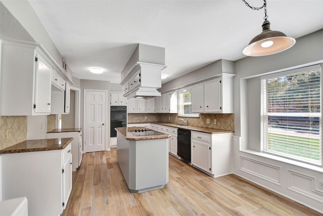 kitchen with light hardwood / wood-style floors, a center island, white cabinetry, and black appliances