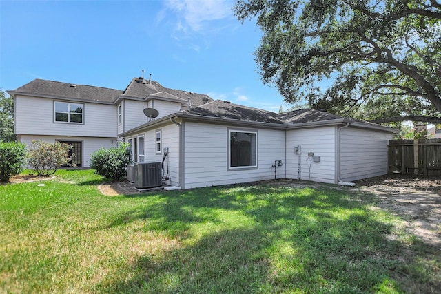 rear view of property featuring cooling unit and a lawn