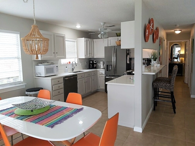 kitchen with black dishwasher, white cabinetry, pendant lighting, and stainless steel fridge