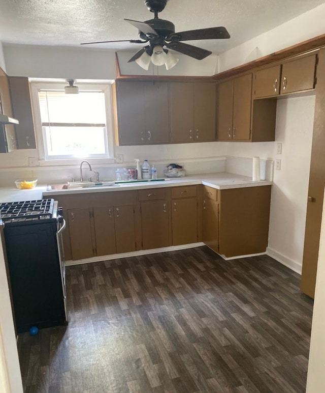 kitchen with dark wood-type flooring, black range oven, a textured ceiling, sink, and ceiling fan