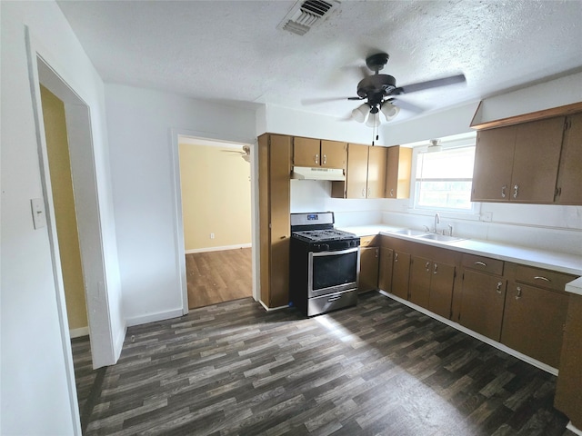 kitchen featuring stainless steel range with gas stovetop, sink, ceiling fan, dark hardwood / wood-style floors, and a textured ceiling