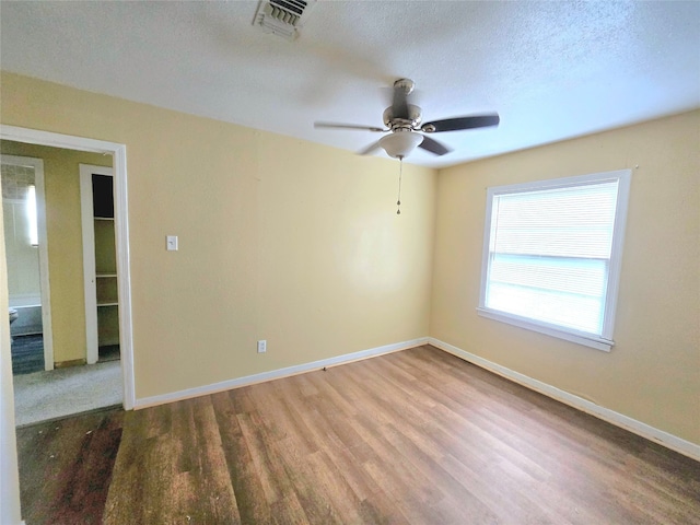 spare room with a textured ceiling, wood-type flooring, and ceiling fan