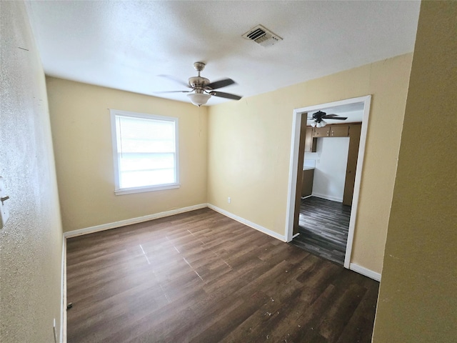 unfurnished room featuring dark wood-type flooring and ceiling fan