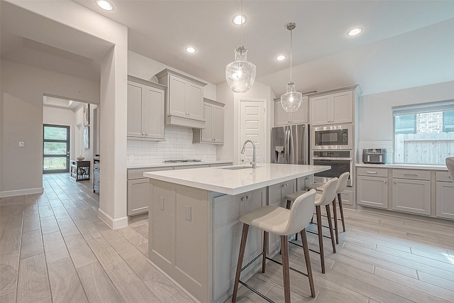 kitchen featuring a wealth of natural light, appliances with stainless steel finishes, light hardwood / wood-style flooring, and an island with sink