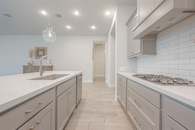 kitchen with backsplash, appliances with stainless steel finishes, pendant lighting, gray cabinetry, and sink