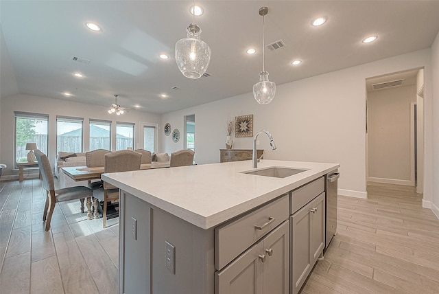 kitchen featuring light hardwood / wood-style floors, hanging light fixtures, sink, and a kitchen island with sink