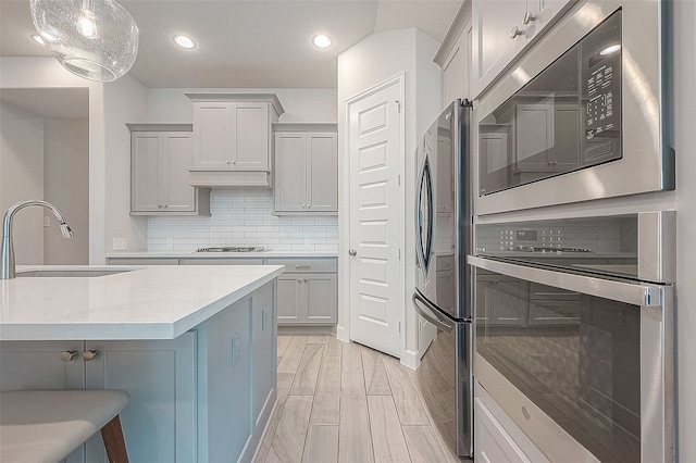 kitchen with decorative backsplash, a kitchen breakfast bar, stainless steel appliances, sink, and pendant lighting