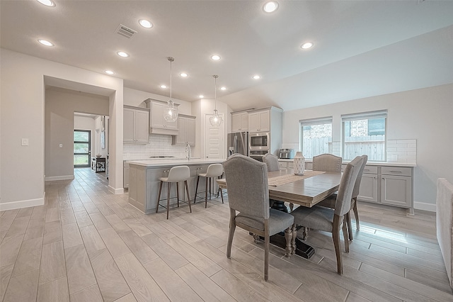 dining area featuring lofted ceiling and light wood-type flooring